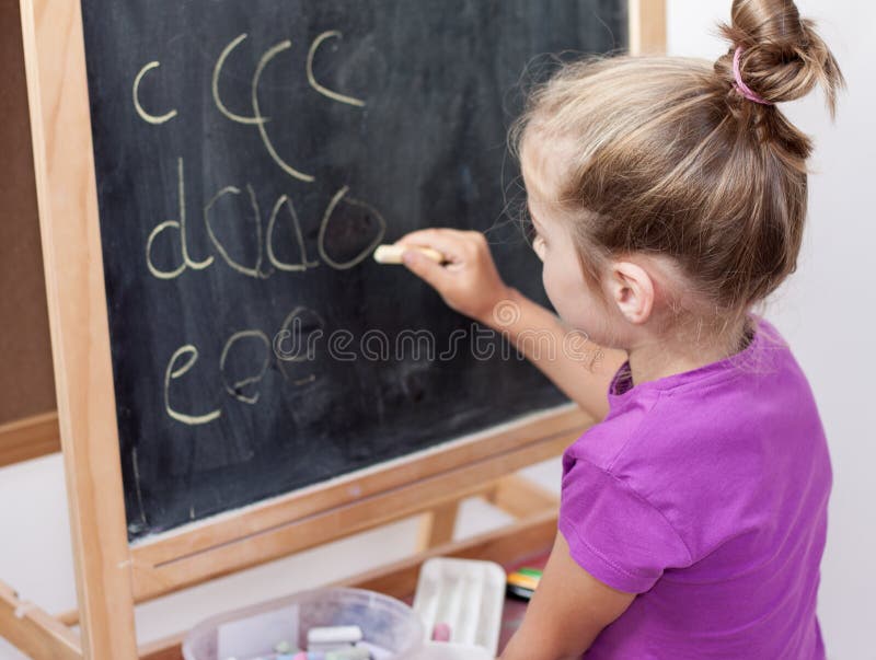 Jeune fille apprenant à écrire des lettres sur le tableau noir