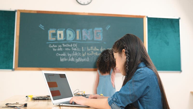 Jeune fille asiatique écrire une invite d'ingénierie en utilisant un logiciel ai en classe. pédagogie. Fille écrire une invite d'ingénierie en utilisant un logiciel ou un système de programmation ai pour générer de l'ai sur table avec la carte principale électronique en classe tige pendant que l'étudiant écrit un plan de développement logiciel.
