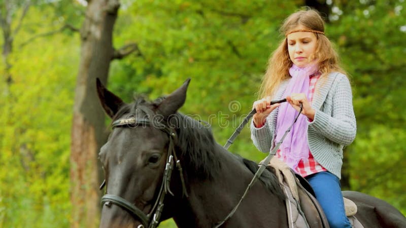 Jeune fille assis sur le cheval noir à l'automne jour de clips vidéos