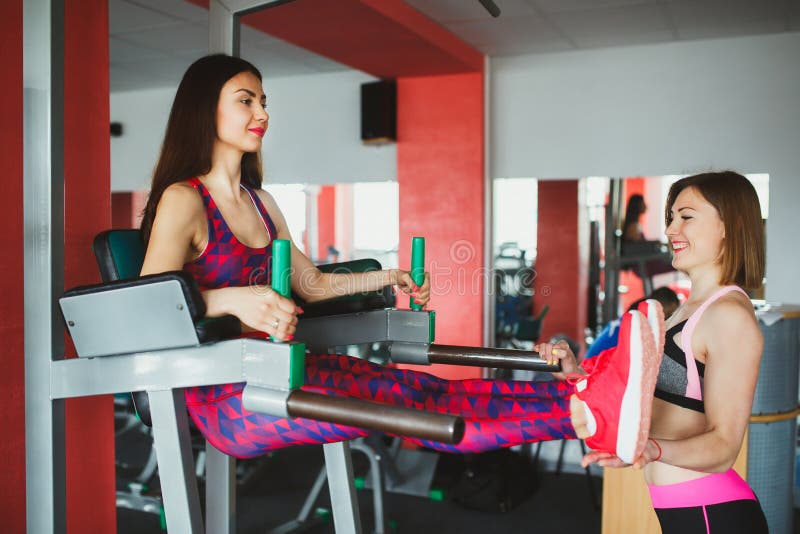 Jeune fille attirante avec l'entraîneur personnel dans le gymnase photo libre de droits Jeune fille attirante avec l'entraîneur personnel dans le gymnase photo libre de droits