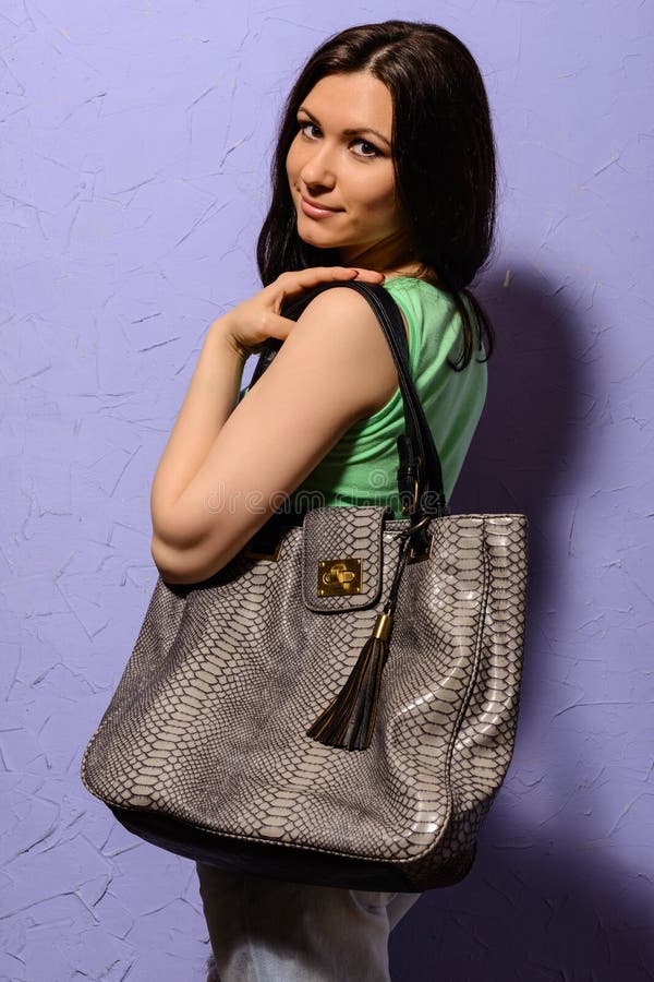 Jeune fille attirante de brune avec le grand sac de la peau de serpent photos libres de droits Jeune fille attirante de brune avec le grand sac de la peau de serpent photos libres de droits