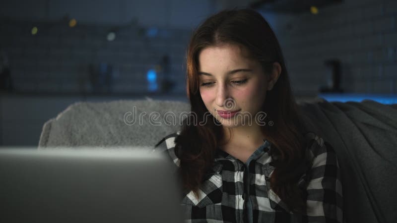 Jeune fille attirante travaillant sur un ordinateur portable à la maison dans la nuit banque de vidéos
