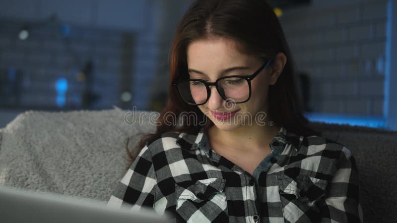 Jeune fille attirante travaillant sur un ordinateur portable à la maison dans la nuit banque de vidéos