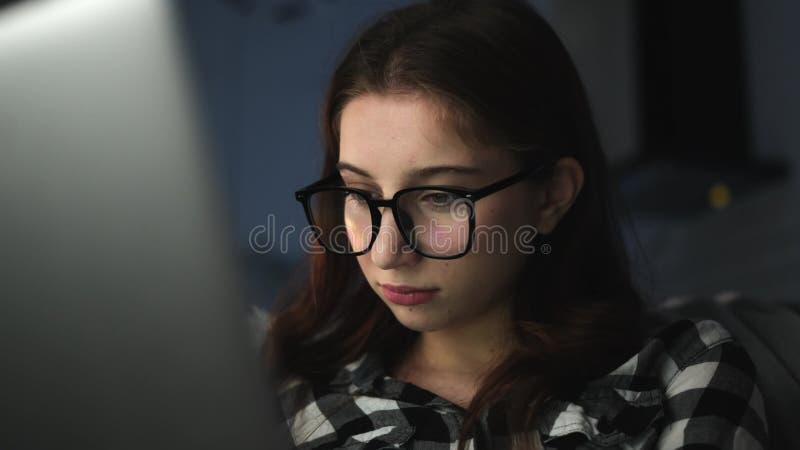 Jeune fille attrayante qui lit des nouvelles horrifiantes sur Internet dans la nuit banque de vidéos