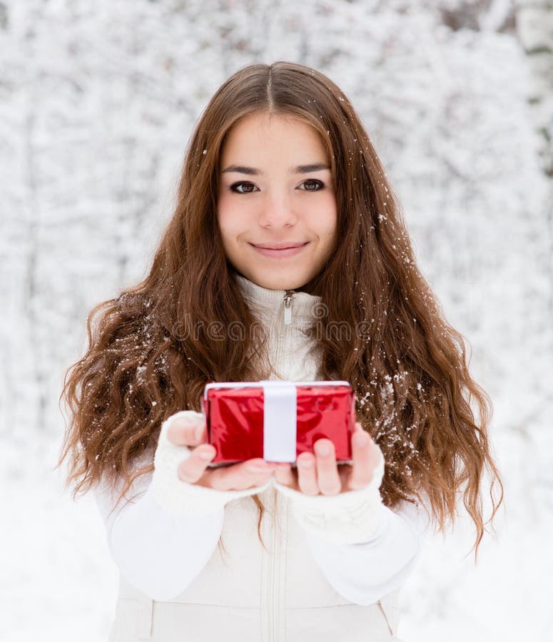 Jeune fille avec le petit boîte-cadeau rouge se tenant dans la forêt d'hiver photographie stock libre de droits Jeune fille avec le petit boîte-cadeau rouge se tenant dans la forêt d'hiver photographie stock libre de droits