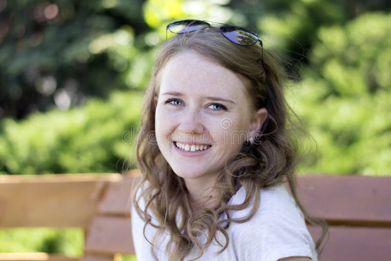 Jeune fille avec un sourire sur le banc images stock Jeune fille avec un sourire sur le banc images stock