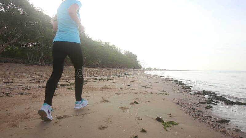 Jeune fille courue le long de la plage au lever de soleil