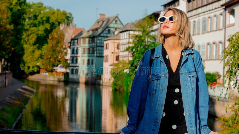 Jeune fille dans des jeans veste et lunettes de soleil sur la rue de Strasbourg images libres de droits Jeune fille dans des jeans veste et lunettes de soleil sur la rue de Strasbourg images libres de droits