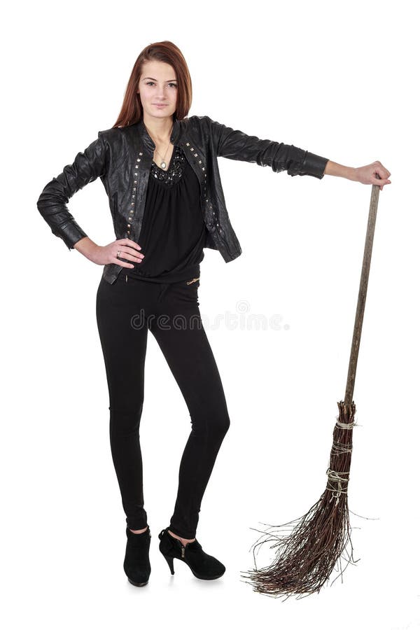 Young girl in black leather jacket and high heels holding wooden wicked broom over white background. Young girl in black leather jacket and high heels holding wooden wicked broom over white background