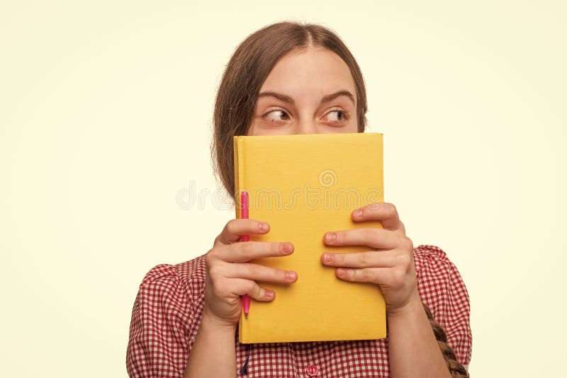 Jeune fille de l'école se cachant derrière la lecture livre d'éducation pour obtenir la connaissance isolé sur blanc images libres de droits