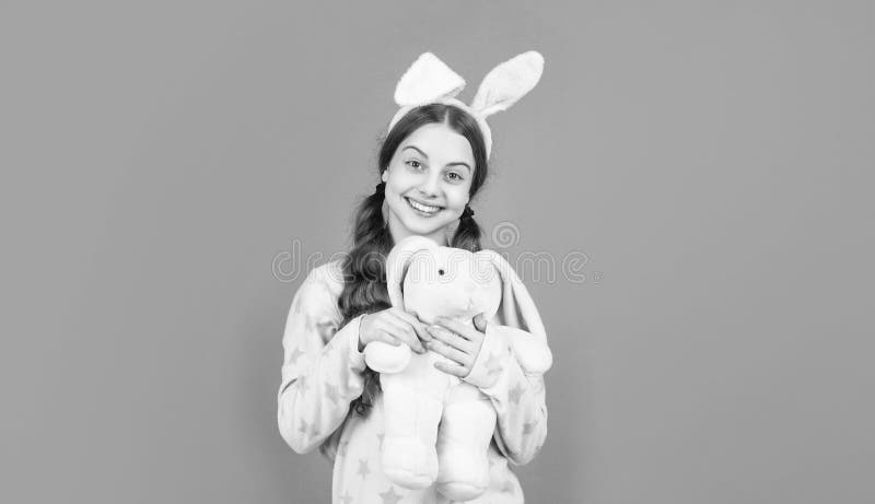Jeune fille de pâques heureux dans des oreilles lapin lapin lapin et pyjama jouer avec jouet Pâques images libres de droits