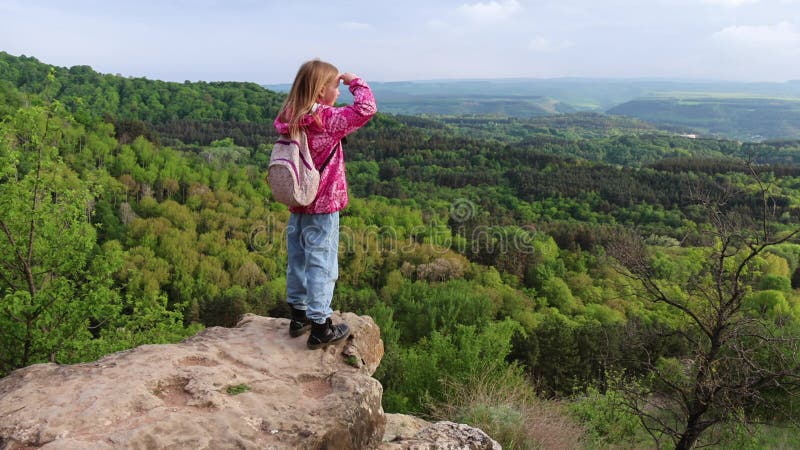 Jeune fille debout sur une falaise rocheuse regardant un paysage forestier panoramique clips vidéos