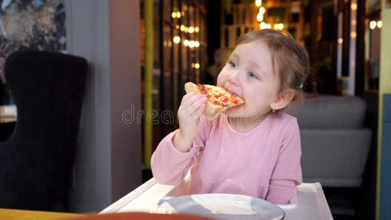 Jeune fille dégustant une tranche de pizza dans une pizzeria cosy banque de vidéos