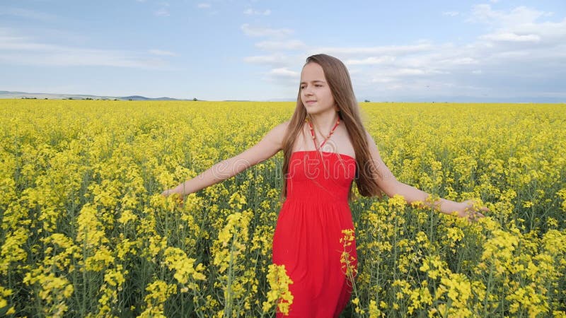 Jeune fille en traversant le gisement de canola face à la caméra banque de vidéos