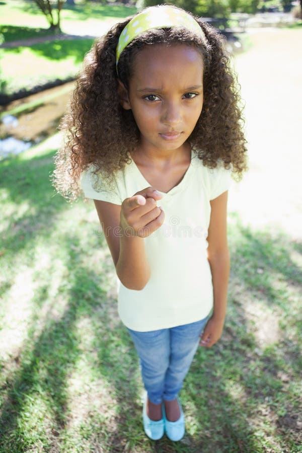 Jeune fille fronçant les sourcils et se dirigeant à l'appareil-photo en parc un jour ensoleillé