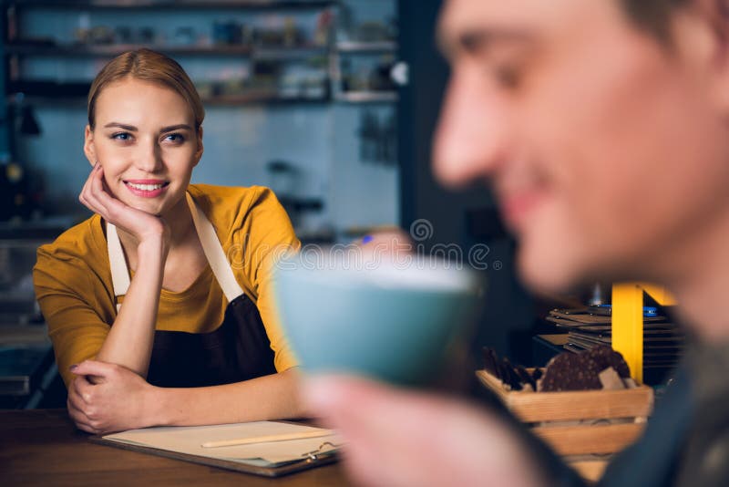 Jeune fille heureuse observant au client en café photo libre de droits Jeune fille heureuse observant au client en café photo libre de droits