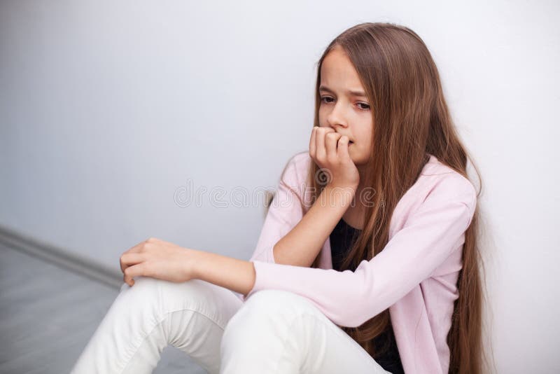 Jeune fille inquiétée d'adolescent s'asseyant sur le plancher par le mur