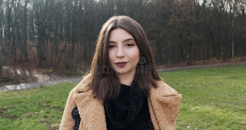 Jeune jeune fille joyeuse qui brille en marchant sur la pelouse verte dans le parc d'automne Une jeune femme attrayante marche et banque de vidéos