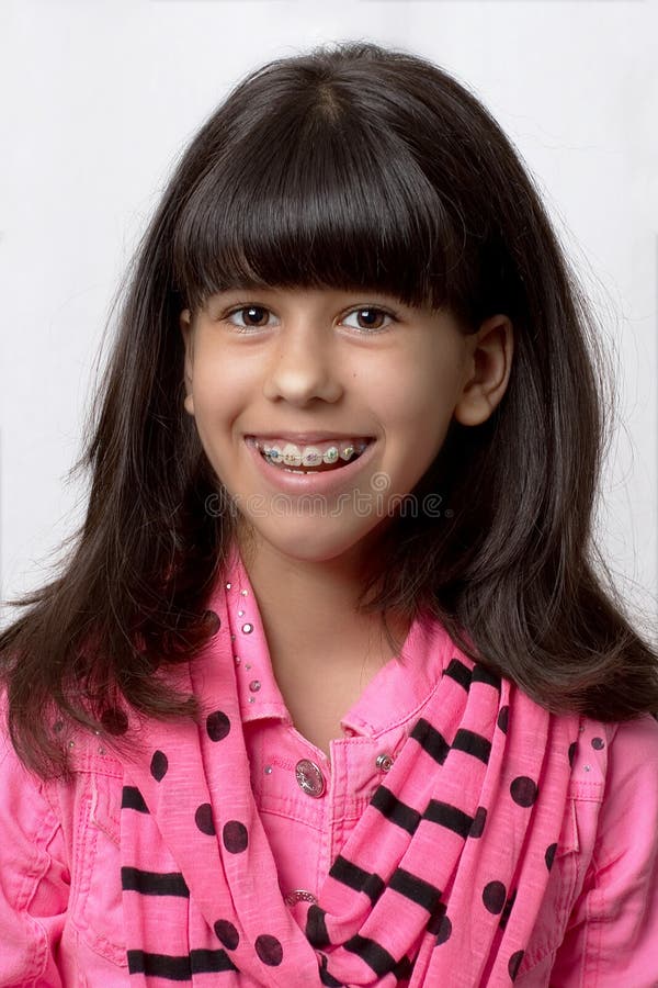 Jeune fille latine souriant avec les accolades colorées photographie stock Jeune fille latine souriant avec les accolades colorées photographie stock