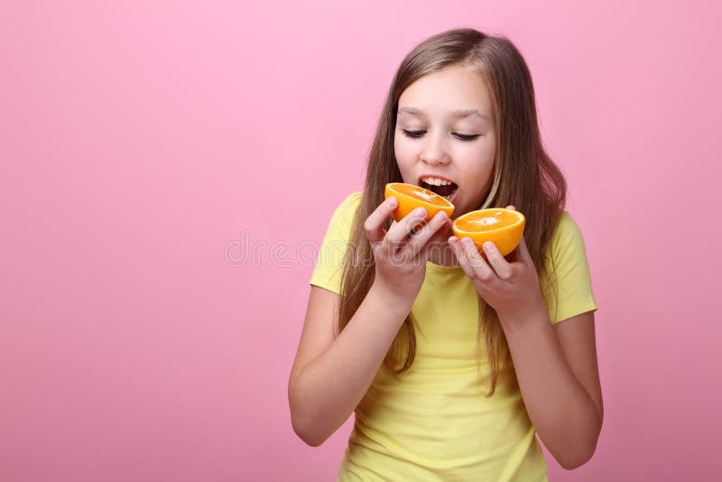 Jeune fille mangeant du fruit orange photos libres de droits Jeune fille mangeant du fruit orange photos libres de droits
