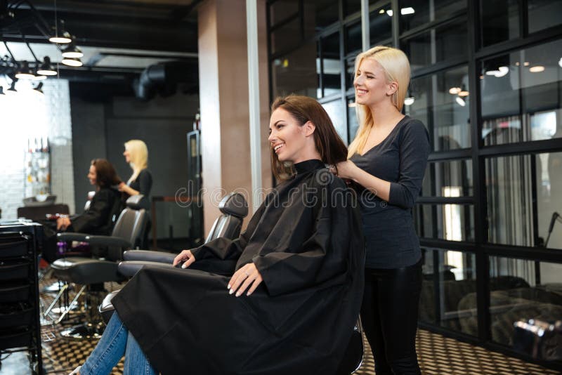 Jeune fille parlant avec le coiffeur dans le salon de beauté image libre de droits Jeune fille parlant avec le coiffeur dans le salon de beauté image libre de droits