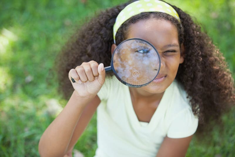 Jeune fille regardant par la loupe en parc image libre de droits
