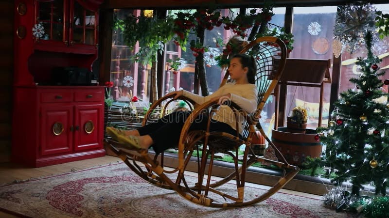 Jeune fille se balade sur une chaise à bascule près de noël banque de vidéos