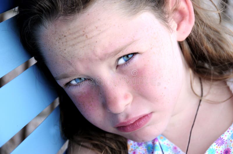 Young freckle faced girl sitting outside on bench looking hot and tired. Young freckle faced girl sitting outside on bench looking hot and tired