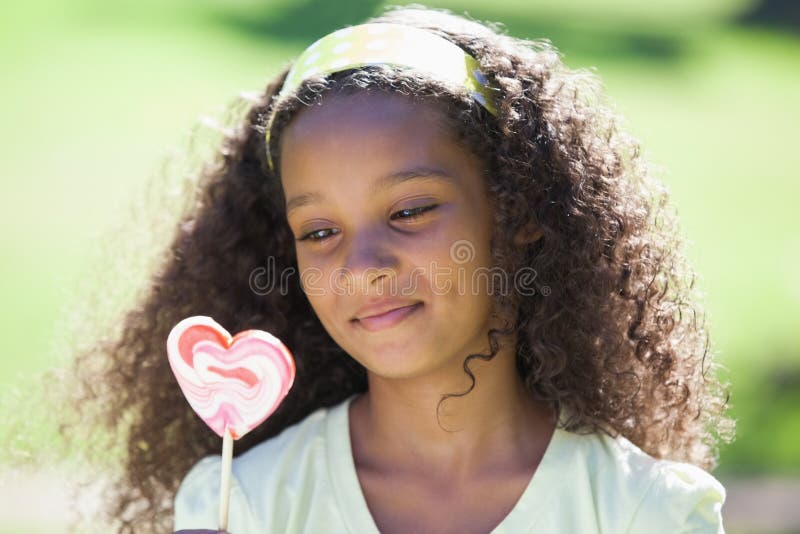 Jeune fille tenant une lucette de coeur en parc image stock