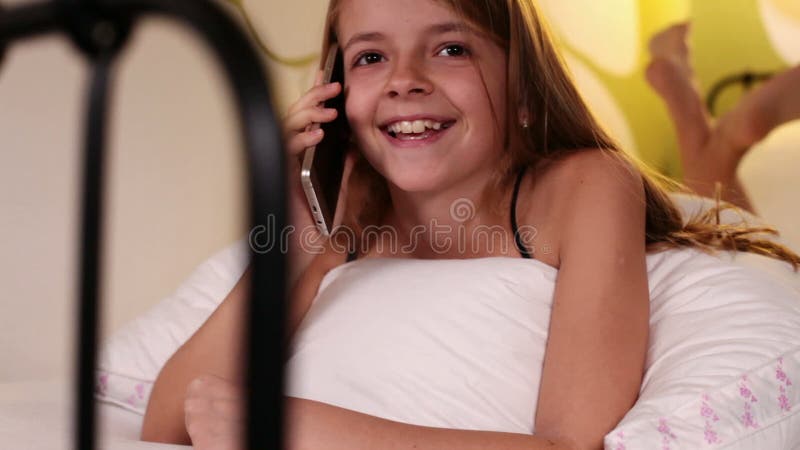 Jeune fille à l'aide du smartphone parlant dans le lit banque de vidéos