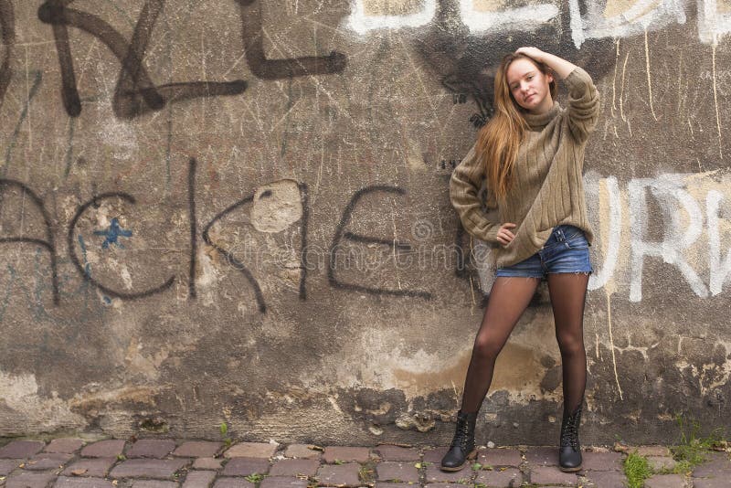 Jeune fille à la mode posant près du vieux mur image stock Jeune fille à la mode posant près du vieux mur image stock