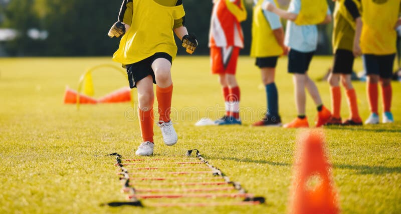 Jeune footballer dans les vêtements de sport jaunes au stage de formation sur le terrain de football d'herbe