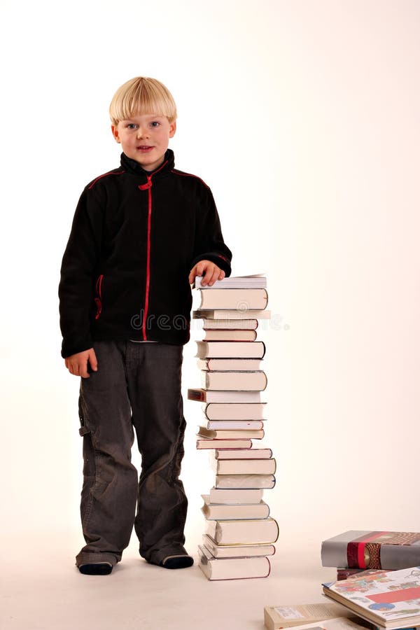 A young boy standing next to a pile of new books on a white background. A young boy standing next to a pile of new books on a white background.