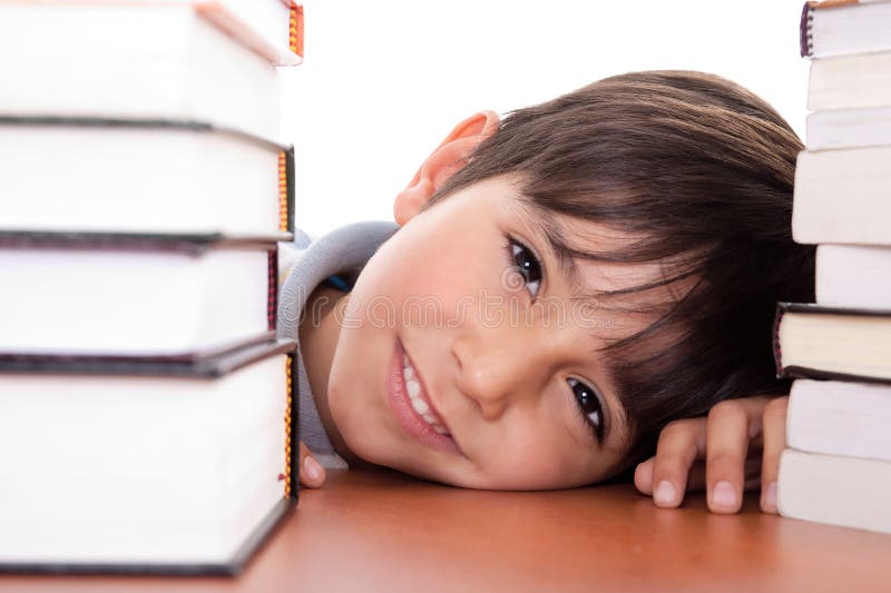 Jeune garçon d'école heureux entouré par des livres images stock Jeune garçon d'école heureux entouré par des livres images stock