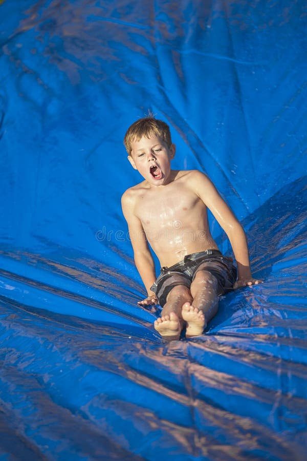 Jeune garçon glissant vers le bas un glissement et une glissière dehors photo libre de droits Jeune garçon glissant vers le bas un glissement et une glissière dehors photo libre de droits