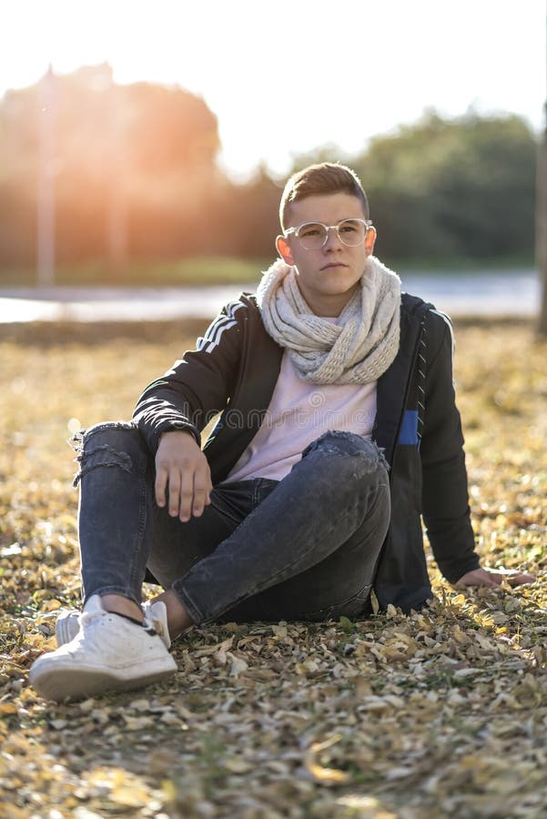 Jeune garçon heureux adolescent assis par terre devant la caméra en portrait posé photos libres de droits