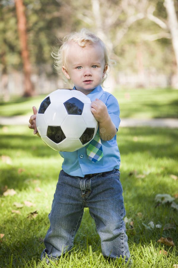 Jeune garçon mignon jouant avec du ballon de football en parc photographie stock Jeune garçon mignon jouant avec du ballon de football en parc photographie stock