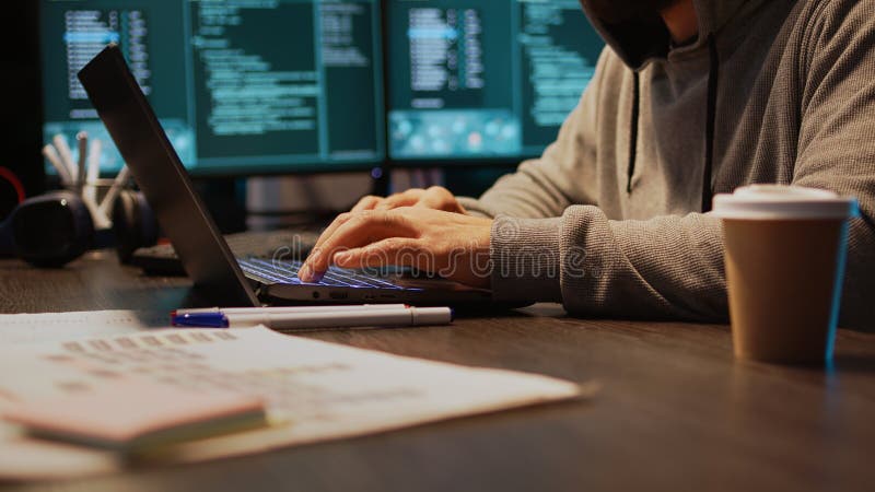 Young hacker breaking into database server on computer, using development malware to steal big data from system. Working at night with multiple monitors to hack important information. Handheld shot. Young hacker breaking into database server on computer, using development malware to steal big data from system. Working at night with multiple monitors to hack important information. Handheld shot.