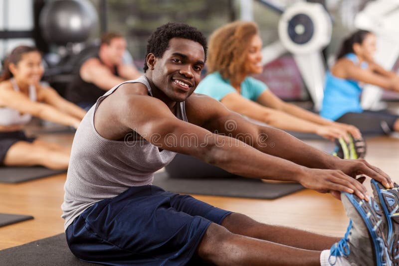 Jeune homme afro-américain s'étirant dans un gymnase photographie stock libre de droits Jeune homme afro-américain s'étirant dans un gymnase photographie stock libre de droits