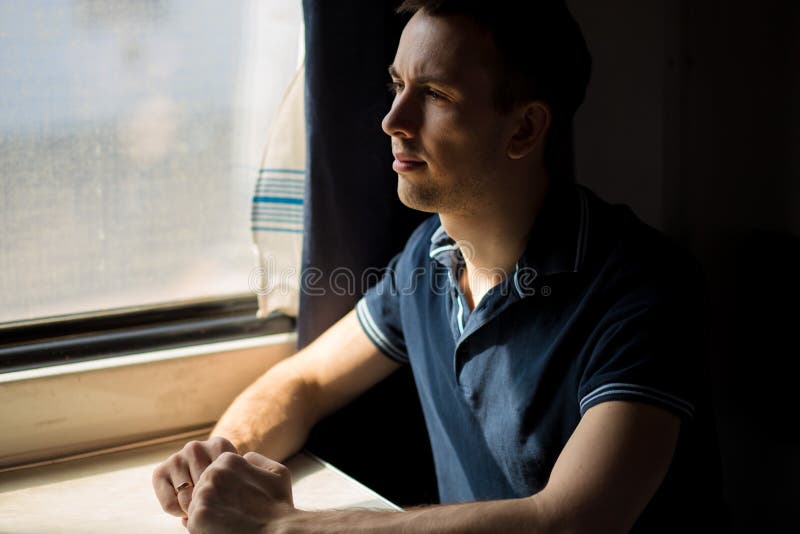 Jeune homme appréciant le voyage de train - laissant sa voiture à la maison, regarde hors de la fenêtre, a le temps pour admirer photo stock Jeune homme appréciant le voyage de train - laissant sa voiture à la maison, regarde hors de la fenêtre, a le temps pour admirer photo stock