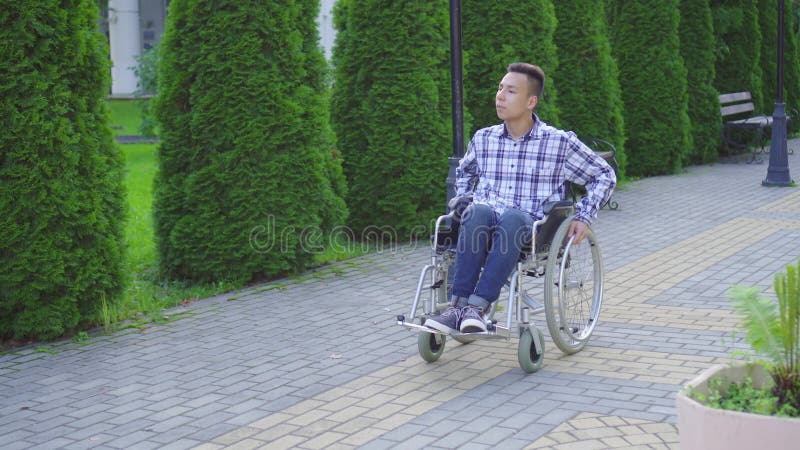 Jeune homme asiatique handicapÃ© en fauteuil roulant dans le parc