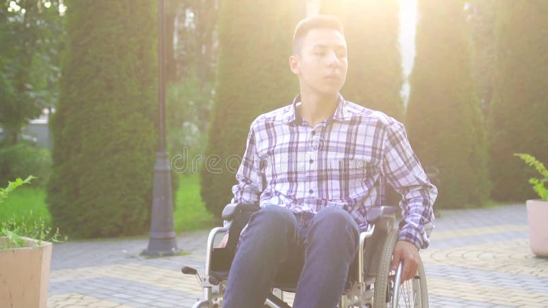 Jeune homme asiatique handicapé en fauteuil roulant dans le parc Rayon solaire lent