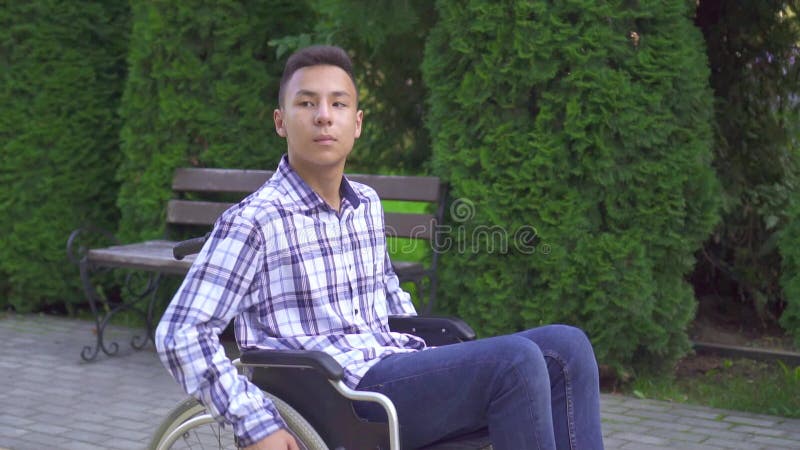 Jeune homme asiatique handicapé en fauteuil roulant dans le parc slow mo
