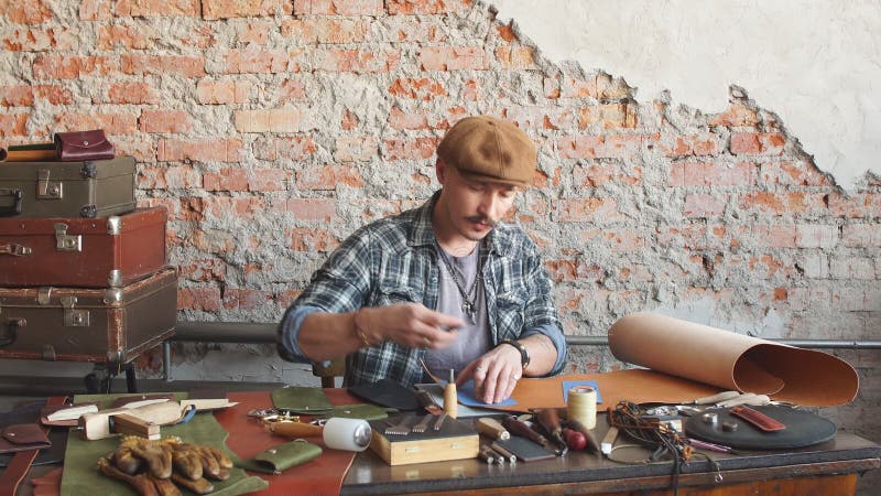 Jeune homme assidu travaillant avec le cuir utilisant ouvrer des outils