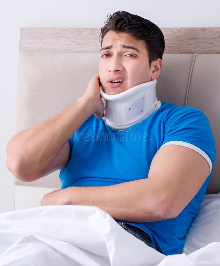 Jeune homme avec la blessure de cou dans le lit image stock Jeune homme avec la blessure de cou dans le lit image stock