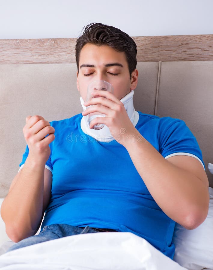 Jeune homme avec la blessure de cou dans le lit images libres de droits Jeune homme avec la blessure de cou dans le lit images libres de droits