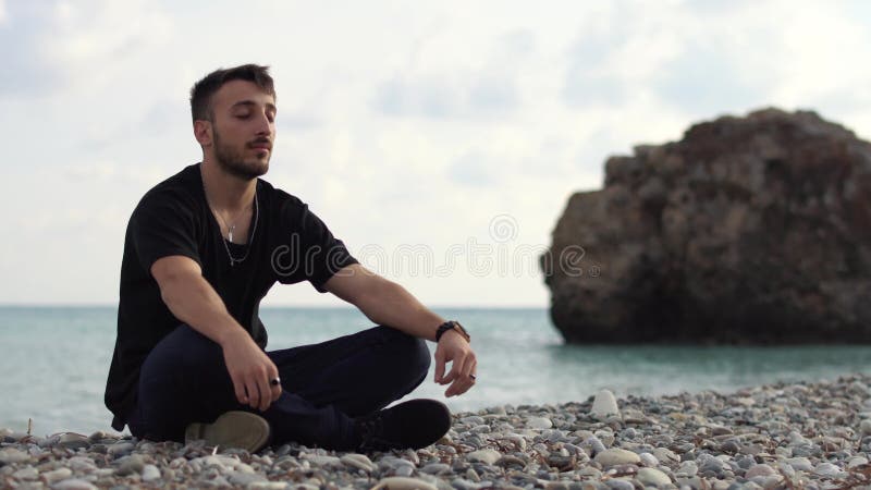 Jeune homme avec les yeux ferm? s se reposant et d? tendant dans le style de yoga pr? s de la vue de c? t? stup? fiante de mer Type be clips vidéos