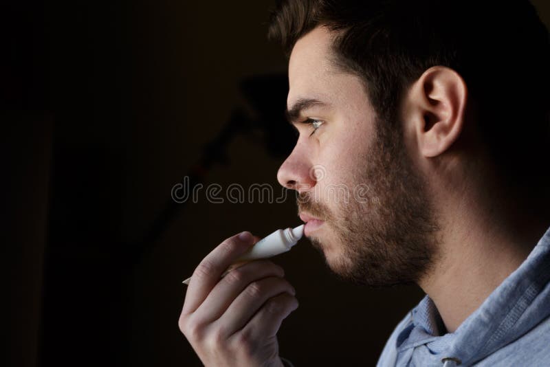 Jeune homme avec une barbe réparant ses lèvres endommagées avec la crème hydratante photos libres de droits Jeune homme avec une barbe réparant ses lèvres endommagées avec la crème hydratante photos libres de droits
