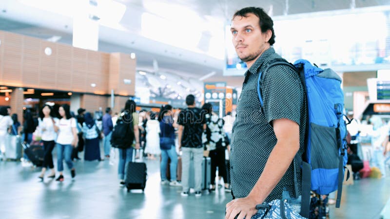 Jeune homme barbu avec le sac à dos tirant la valise dans le terminal d'aéroport moderne Type beau de déplacement marchant loin a photos libres de droits Jeune homme barbu avec le sac à dos tirant la valise dans le terminal d'aéroport moderne Type beau de déplacement marchant loin a photos libres de droits
