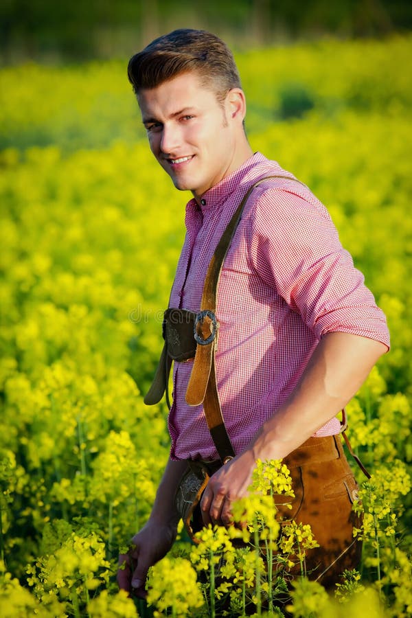 Jeune homme bavarois debout dans un champ de fleurs jaunes